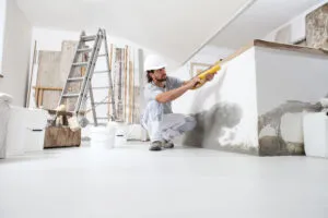 construction worker plasterer man uses caulking gun in building site of home renovation with tools and building materials on the floor